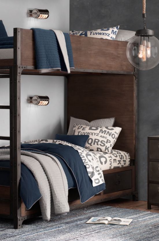 a dark stained industrial bunk bed unit with a ladder with matching metal wall sconces over each bed