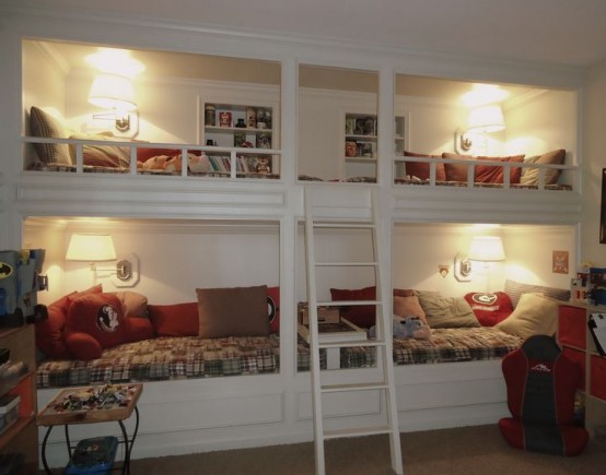 a white vintage bunk bed set of four, cozy wall lamps and a single ladder plus built-in shelves over each upper bed