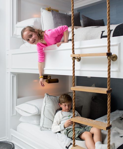 a kids' bunk bed setup with wall sconces and a rope ladder to reach each sleeping space
