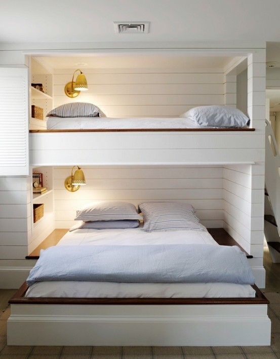 a unique bunk bed unit for two with a retractable bed in the lower part, wall sconces and built-in shelves over the beds