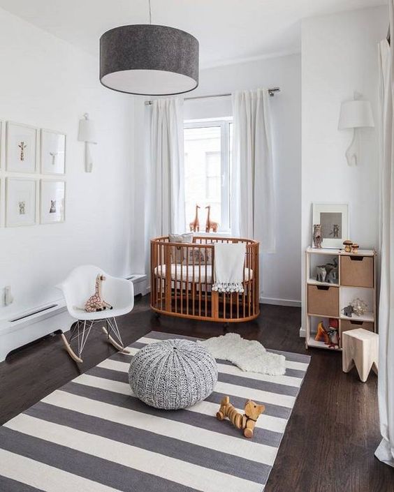 a stylish grey and white nursery with neutral furniture, a wooden crib, some simple textiles and a gallery wall is very welcoming