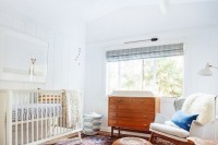 a serene and cozy mid-century modern nursery with stained and white furniture, a printed rug and faux fur is a stylish space