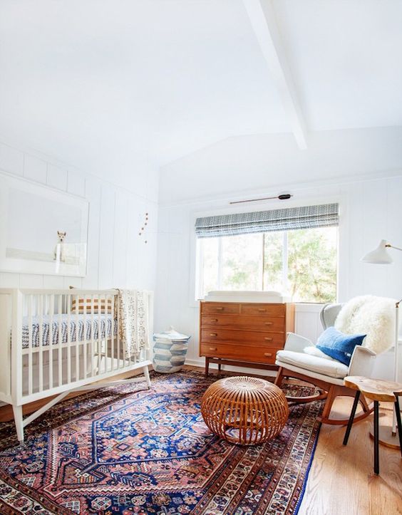 a serene and cozy mid-century modern nursery with stained and white furniture, a printed rug and faux fur is a stylish space