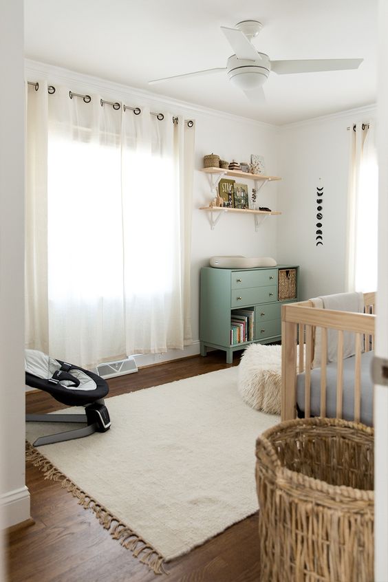 a neutral farmhouse nursery with light-colored furniture, a green changing table, neutral textiles is a very cozy and welcoming room