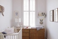 a neutral and peaceful nursery with white and light colored furniture, artworks and faux taxidermy plus lots of toys