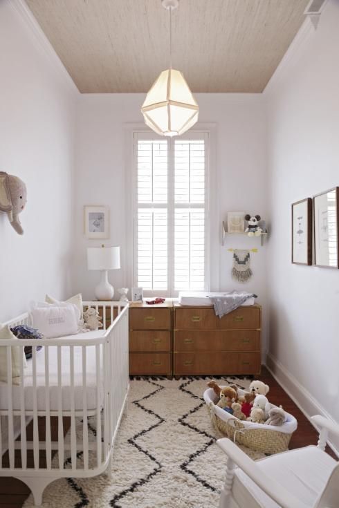 a neutral and peaceful nursery with white and light colored furniture, artworks and faux taxidermy plus lots of toys