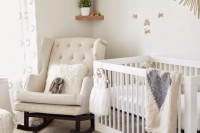 a neutral nursery with chic and cozy neutral furniture, triangle wooden shelves, a sunburst mirror and some simple bedding