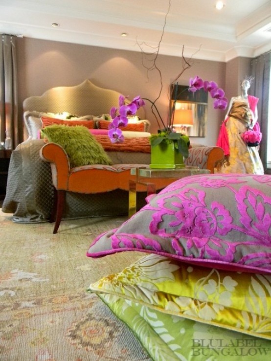 a bright glam bedroom with a refined upholstered bed, colorful pillows and bedding, bright orchids and statues