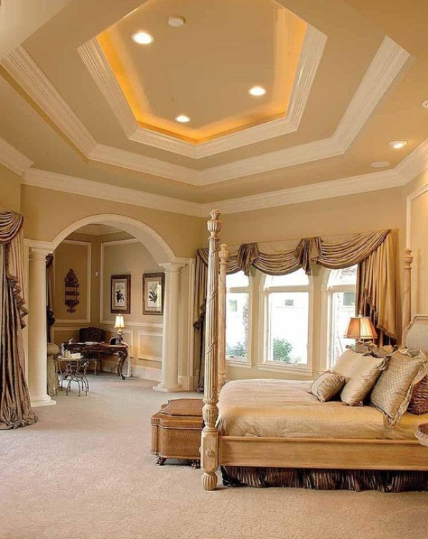 a refined warm colored bedroom with a carved ceiling, a refined bed, a chic home office space and lots of lights