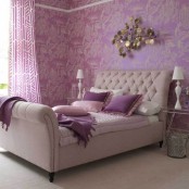 a lilac, purple, gold glam bedroom with a refined upholstered bed, cool textiles, a chic sculpture on the floor