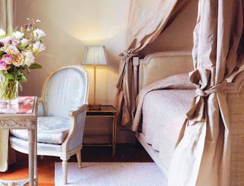 a refined and glam pink bedroom with luxurious textiles, exquisite furniture and lamps plus blooms in a vase