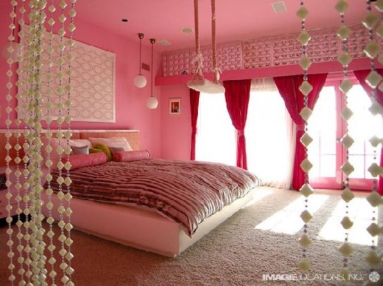 a glam and girlish pink and red bedroom with pink walls, red curtains, hanging crystals and printed textiles