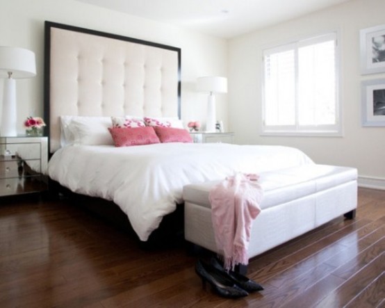 a modern glam bedroom with white walls, an upholstered bed with a statement headboard, a white bench with storage