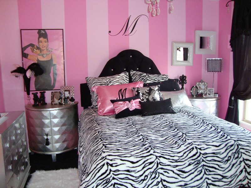 a glam pink, black and white bedroom with a striped statement wall, printed bedding, quirky furniture pieces