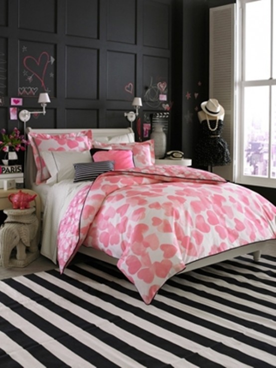 a black, pink and white bedroom with a black statement wall, pink bedding, a striped rug and some girlish decorations