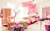 a glam pink bedroom with printed textiles, bright printed ottomans, a pink canopy and screen plus a pink vanity table