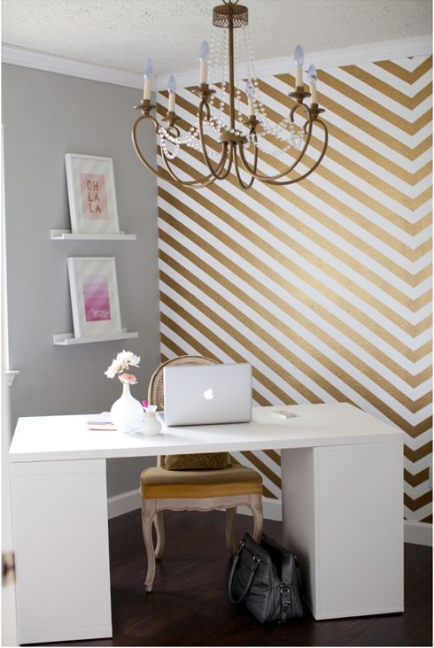 a gold and white chevron accent wall and a gold chair glam up the room and make it look chic and bold