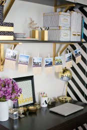 a glam working space in black and white spruced up with gold, with black and gold shelves, gold candleholders, a gold table lamp and some pencil holders is cool