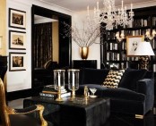 a refined black and white living room with a black bookcase, a black velvet sofa, a black coffee table, a black and gold chair, a gold vase and candleholders