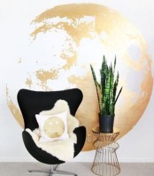 a gold and white earth print is a beautiful and modern glam alternative to a usual artwork, a small gold side table with a potted plant and a gold print pillow is a lovely addition here