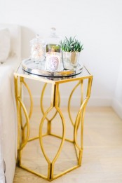a refined side table with a beautiful gold base, a mirror tray with potted plants and a candle is a lovely touch to an elegant living room