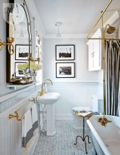 a refined retro bathroom in neutrals, with a black and white gallery wlal, a striped curtain, a refined mirror and gold fixtures and other touches for a glam feel