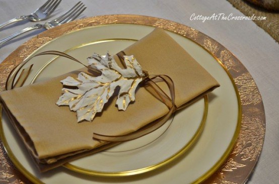 gold rimmed plates, gold napkins, leaves and a charger will add a warm and shiny glow to your fall tablescape