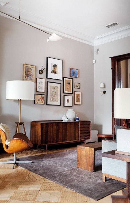 a mid-century modern living room done in neutrals, with stained furniture, a leather chair, a credenza, a gallery wall and table lamps