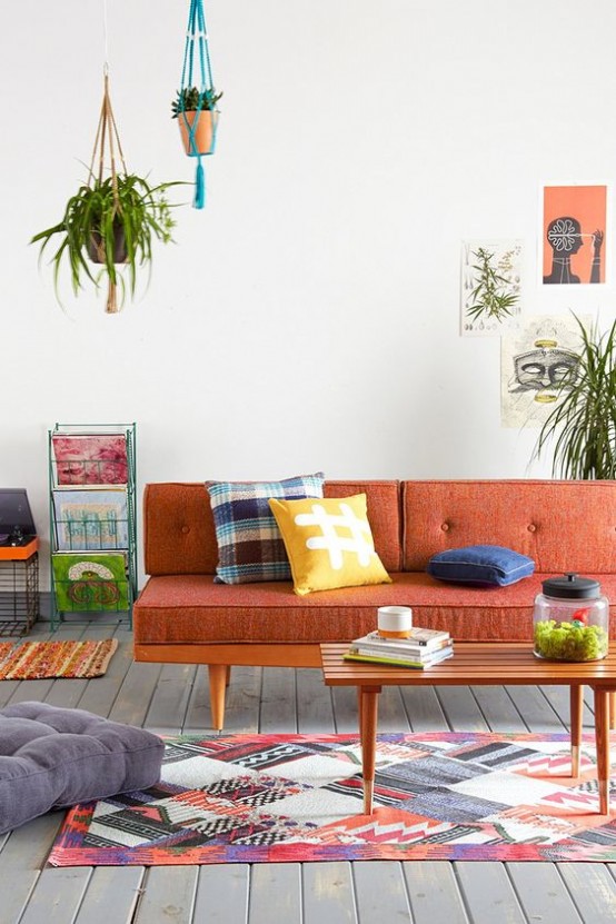 a mid-century modern to boho living room with a rust-colored sofa and bold pillows, a bright rug, potted greenery and shelving units with magazines
