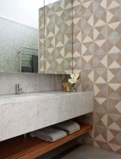 a modern bathroom with geometric tiles on the walls, a white stone vanity, blue tiles on other walls is chic