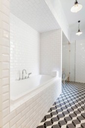 a modern bathroom with white subway tiles on the walls and black and white geometric tiles on the floor is a catchy and chic space