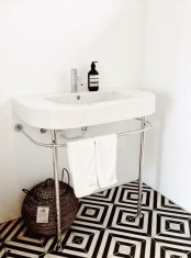 a stylish bathroom with a black and white geometric tile floor and a free-standing sink is chic and bold