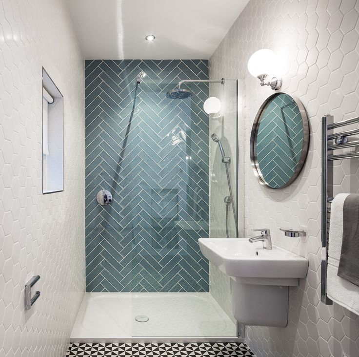 a catchy contemporary bathroom with white hexagon tiles, geometric ones on the floor and blue hrringbone tiles in the shower space