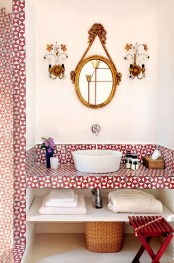 a refined geometric bathroom in red and white, with geo tiles, a built-in vanity with storage, a chic mirror and refined wall sconces