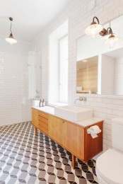 a mid-century modern bathroom with geometric tiles on the floor, white subway tiles on the walls and a wooden vanity with white appliances