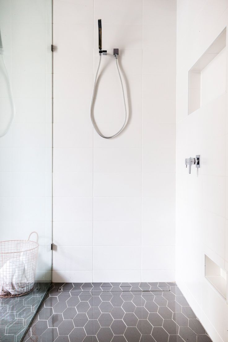 a minimalist bathroom with white large scale tiles on the walls, grey hexagon tiles on the floor is very chic and cool