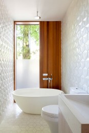 a mid-century modern bathroom with white geometric tiles all over the walls and floor, white appliances is amazing