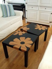 a couple of IKEA Lack tables painted black and with stenciled orange flowers to make a statement and create contrast in the neutral space