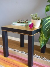 a refined and glam IKEA Lack coffee table painted black, with a gold tabletop and gold decorative nails is a lovely idea with a touch of color