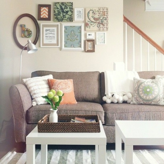a neutral modern farmhouse living room with a taupe sofa and neutral pillows, a small vintage gallery wall and a couple of IKEA Lack tables plus a striped rug