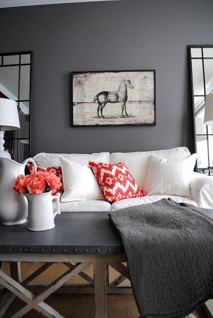 a moody living room with grey walls, a vintage artwork, a white sofa and a grey coffee table and a grey blanket