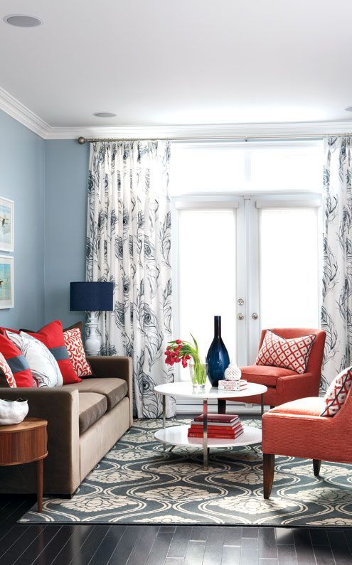a bright coral, grey and white living room with grey walls, a brown sofa, coral chairs, navy touches, printed textiles