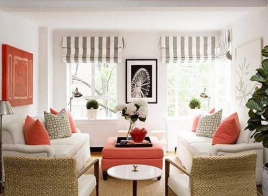 a creamy and coral living room with wicker chairs and grey and white striped shades plus pillows
