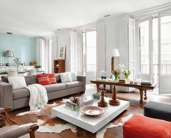 a spacious living room with grey and coral furniture, a white coffee table, a rustic console table, a faux animal skin