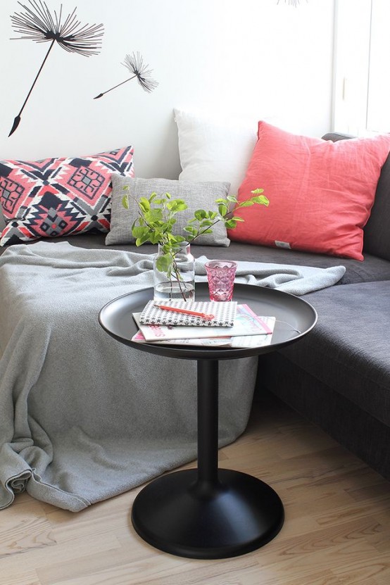 a graphite grey sofa, grey and coral pillows, a black coffee table and fun wallpaper for a stylish living room nook