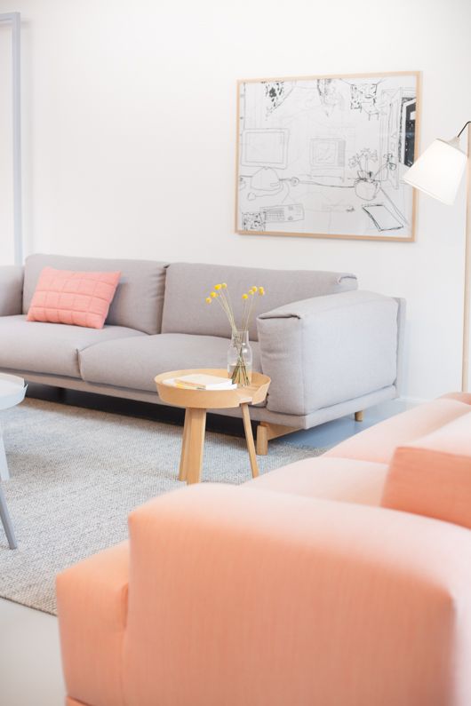 a cute living room with light greys and coral, with an artwork, a coffee table and a floor lamp