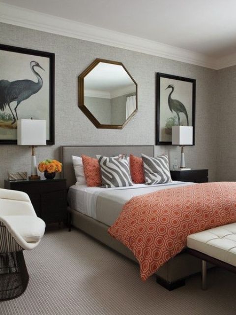 a whimsy bedroom with statement artworks and a geometric mirror, a grey bed, grey and coral bedding and ivory furniture