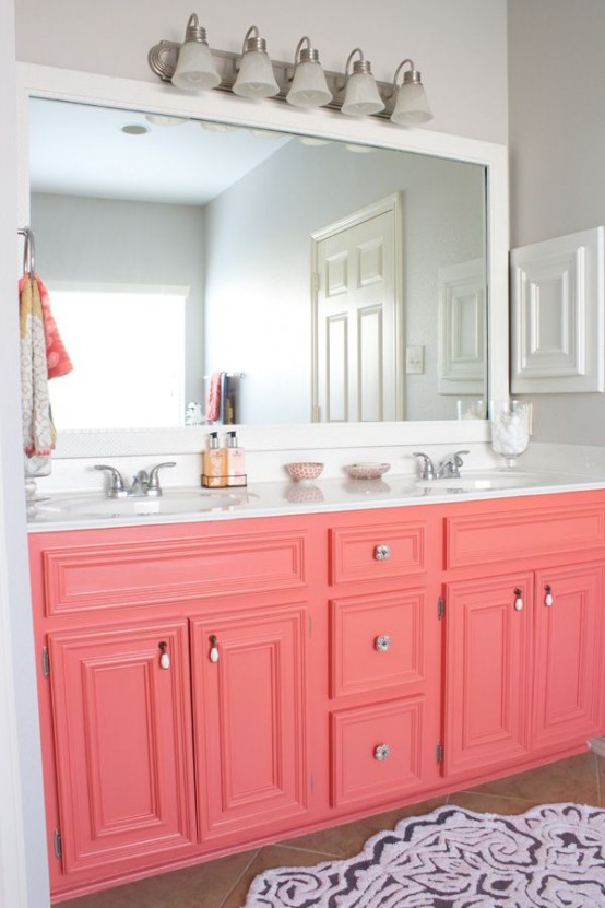 a bright bathroom with dove grey walls, a coral vanity, a white framed mirror and lights