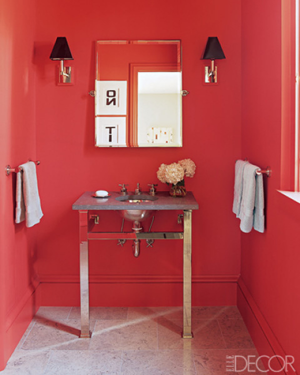 a modern bright red guest toilet with black wall lamps, a lightweight looking vanity with a sink and towels