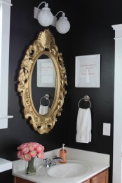 a moody guest toilet done in black and white, with a copper vanity and a mirror in a refined gold mirror frame